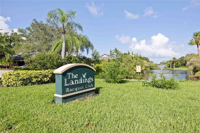 community / neighborhood sign featuring a yard and a water view