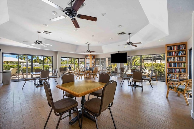 dining room with ceiling fan, hardwood / wood-style floors, and a tray ceiling