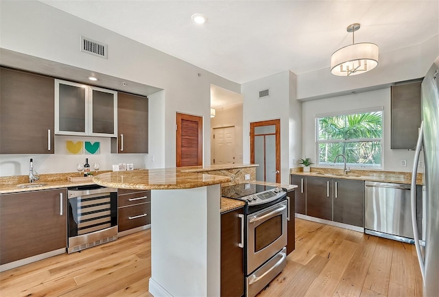 kitchen featuring sink, appliances with stainless steel finishes, dark brown cabinets, wine cooler, and decorative light fixtures