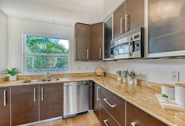 kitchen featuring light stone counters, stainless steel appliances, sink, and dark brown cabinets