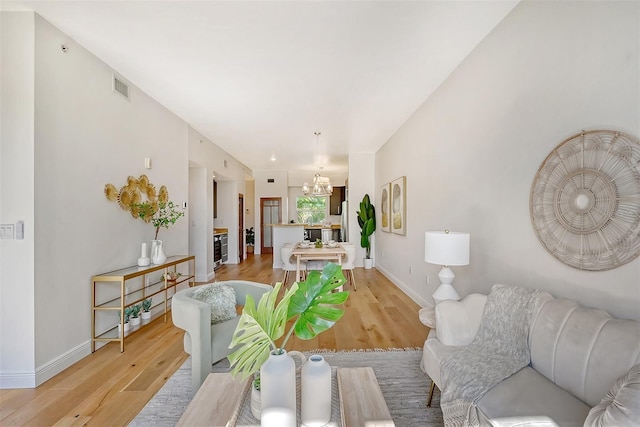 living room with an inviting chandelier and light wood-type flooring