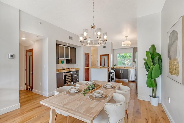 dining room with wine cooler, sink, light hardwood / wood-style floors, and a notable chandelier