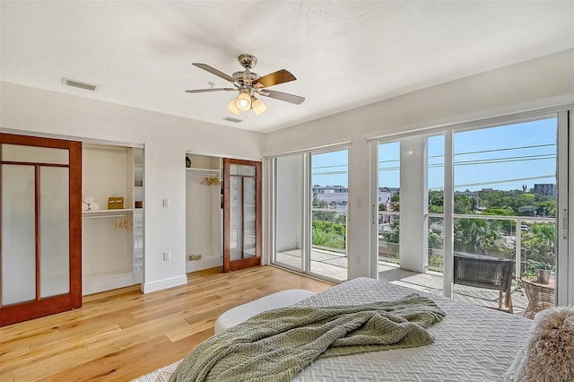 bedroom featuring multiple closets, wood-type flooring, access to exterior, and ceiling fan