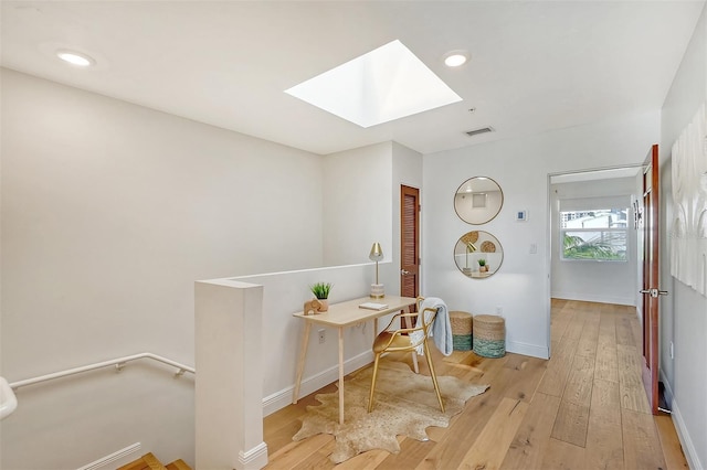 interior space with a skylight and light hardwood / wood-style floors