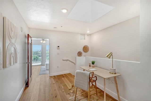 office with a skylight and light hardwood / wood-style floors