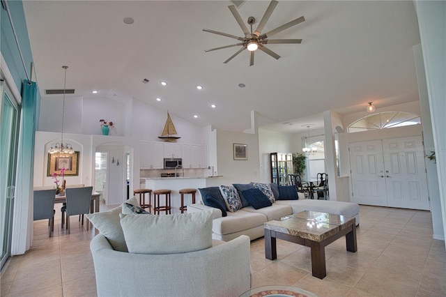 tiled living room featuring high vaulted ceiling and ceiling fan with notable chandelier