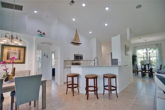 kitchen with kitchen peninsula, white cabinetry, hanging light fixtures, and light tile patterned floors