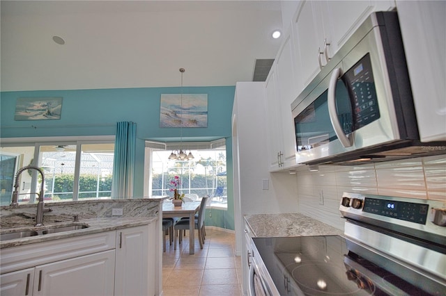 kitchen with white cabinetry, a wealth of natural light, stainless steel appliances, and light stone countertops