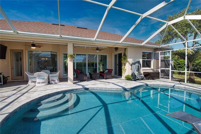 view of swimming pool with ceiling fan, glass enclosure, and a patio