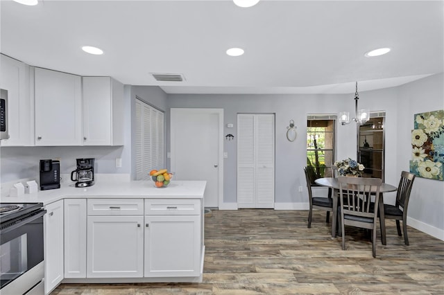 kitchen featuring decorative light fixtures, hardwood / wood-style floors, white cabinetry, range with electric cooktop, and a notable chandelier