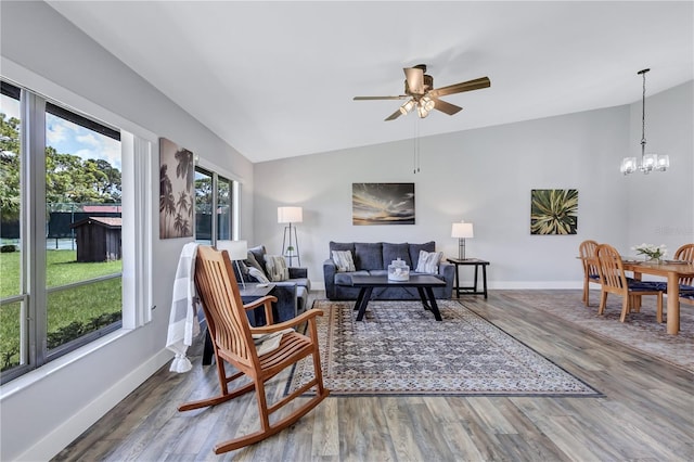 living room with vaulted ceiling, ceiling fan with notable chandelier, and hardwood / wood-style flooring