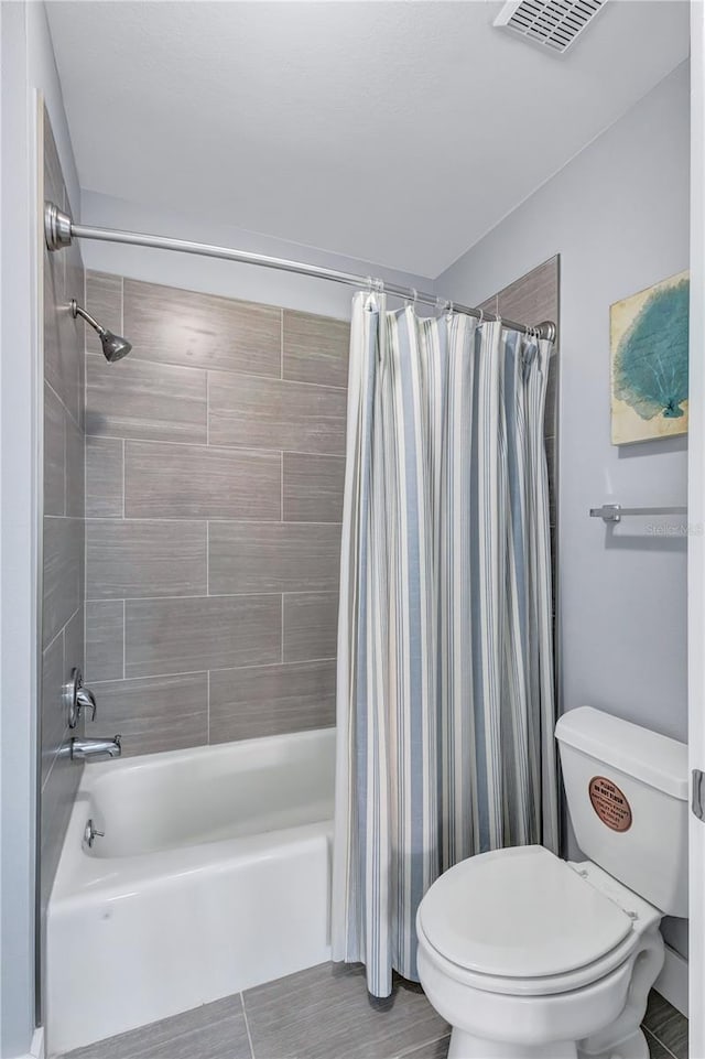 bathroom featuring tile patterned flooring, toilet, and shower / tub combo with curtain