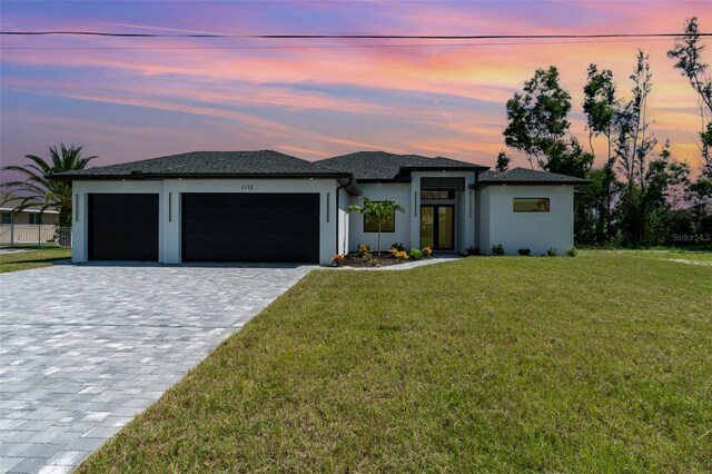 prairie-style home with a garage and a lawn