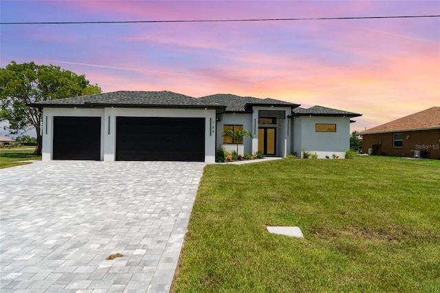 prairie-style home featuring a garage, cooling unit, and a lawn