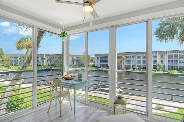 sunroom / solarium featuring a wealth of natural light, ceiling fan, and a water view