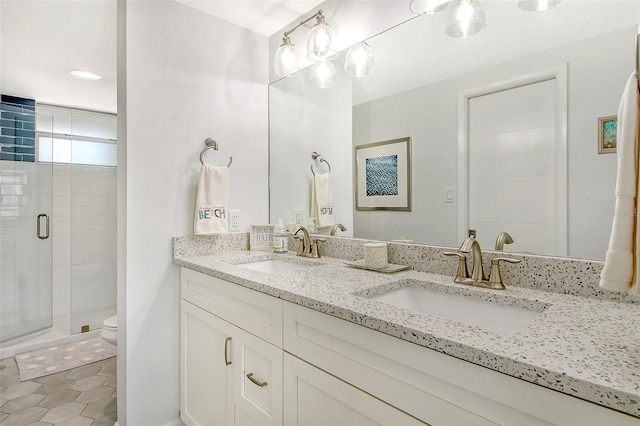 bathroom featuring toilet, double vanity, and a shower with door