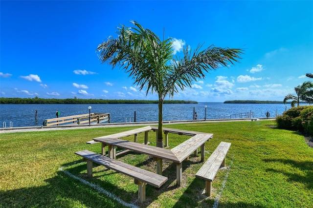 view of dock featuring a lawn and a water view