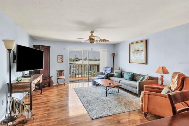 living area featuring a ceiling fan, baseboards, and wood finished floors