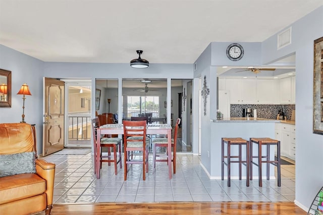 dining area with a ceiling fan, visible vents, baseboards, and light tile patterned floors