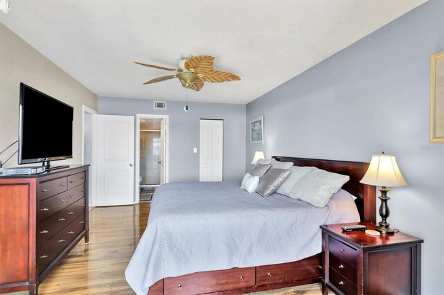 bedroom featuring ceiling fan, light hardwood / wood-style flooring, a closet, and ensuite bathroom