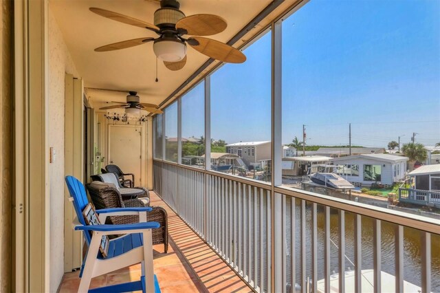 sunroom / solarium featuring ceiling fan and a water view