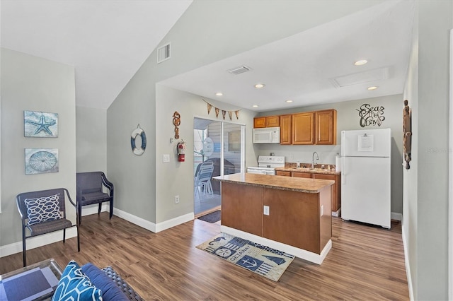 kitchen with hardwood / wood-style floors, sink, a center island, white appliances, and lofted ceiling