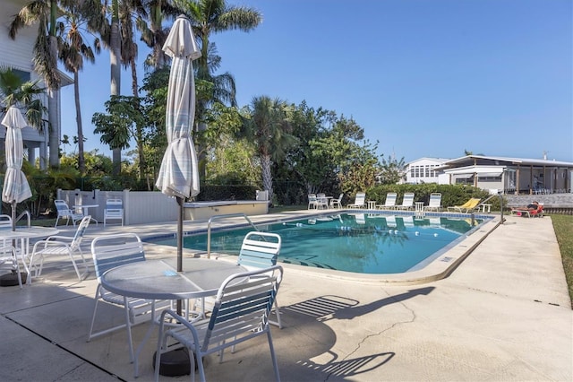 community pool with fence and a patio