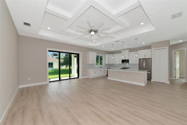 unfurnished living room featuring light wood-type flooring, a raised ceiling, coffered ceiling, and ceiling fan