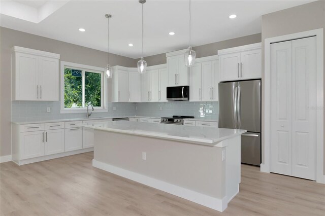 kitchen featuring white cabinets, a center island, light hardwood / wood-style flooring, stainless steel appliances, and tasteful backsplash