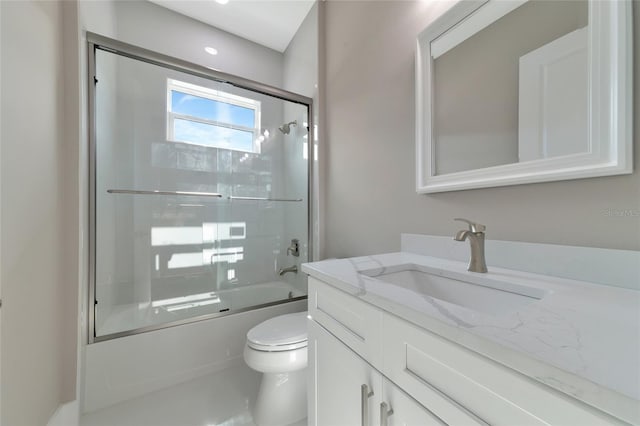 full bathroom with combined bath / shower with glass door, vanity, and toilet