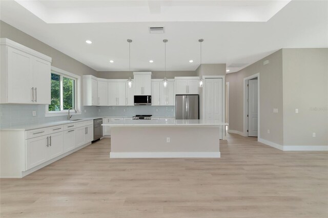 kitchen featuring light hardwood / wood-style flooring, appliances with stainless steel finishes, sink, a kitchen island, and decorative backsplash