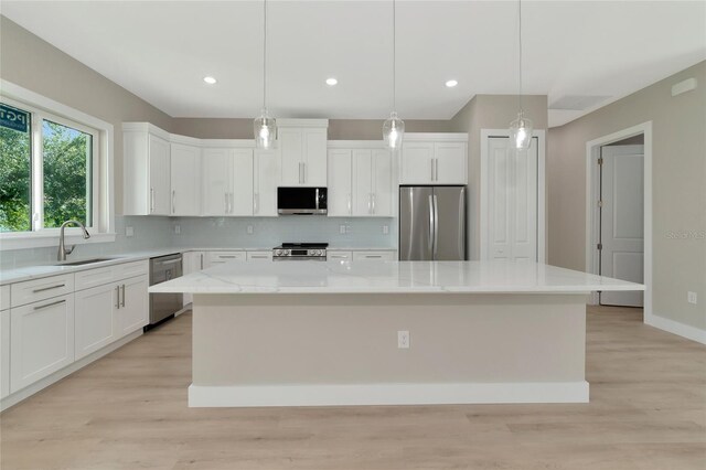 kitchen featuring light hardwood / wood-style flooring, backsplash, a center island, sink, and appliances with stainless steel finishes