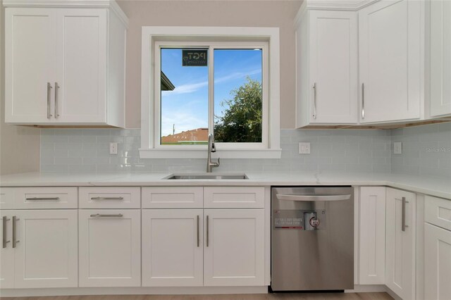 kitchen featuring dishwasher, white cabinets, sink, and decorative backsplash