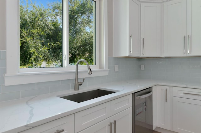 kitchen with dishwasher, decorative backsplash, white cabinetry, and sink