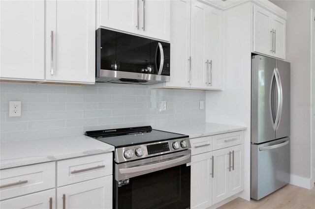 kitchen featuring light hardwood / wood-style floors, light stone countertops, appliances with stainless steel finishes, and tasteful backsplash