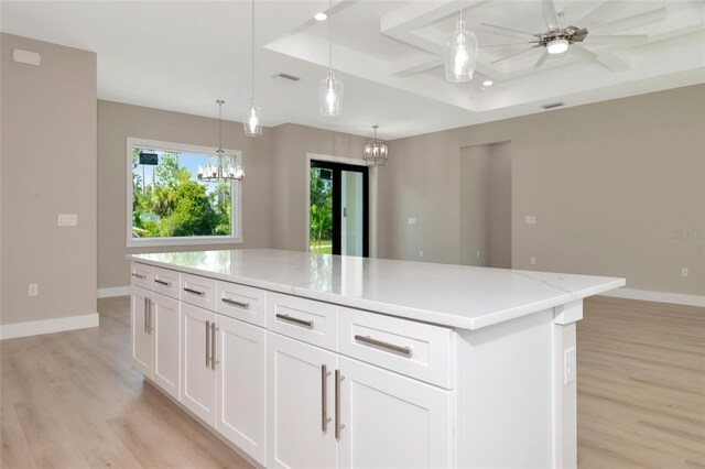 kitchen featuring a kitchen island, ceiling fan with notable chandelier, hanging light fixtures, and light hardwood / wood-style floors