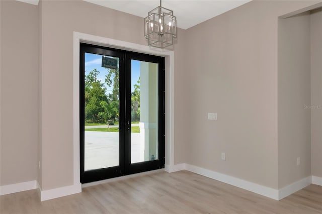 entryway with a wealth of natural light, light hardwood / wood-style flooring, a notable chandelier, and french doors