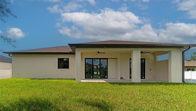 rear view of property featuring ceiling fan, a lawn, and a patio area