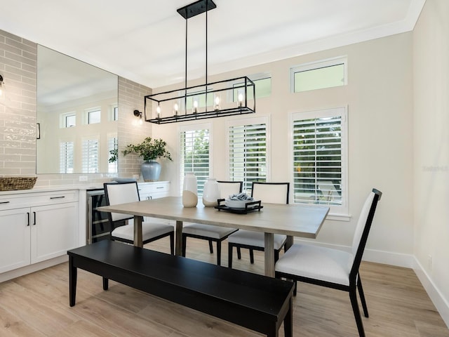 dining room featuring light wood-type flooring, an inviting chandelier, beverage cooler, and a healthy amount of sunlight