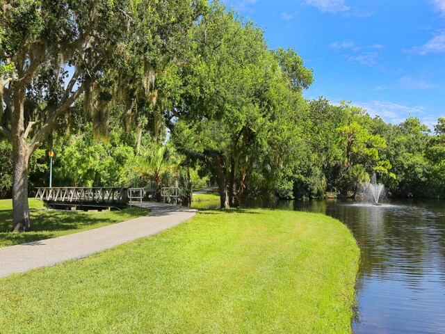 view of property's community with a lawn and a water view