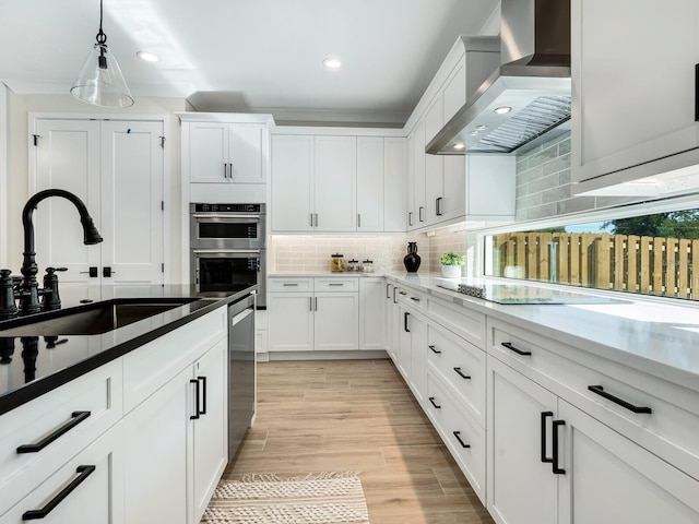 kitchen featuring white cabinetry, sink, and wall chimney range hood