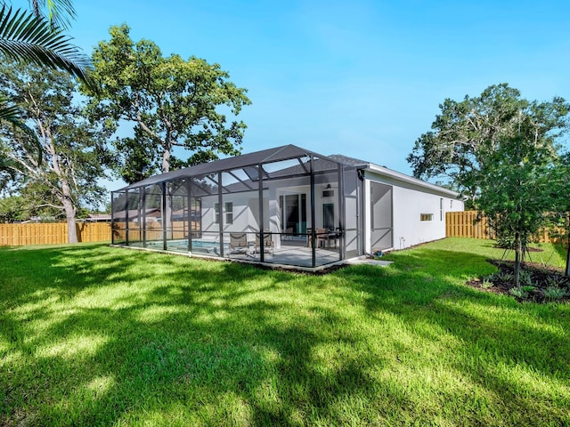 rear view of house with glass enclosure, a patio area, a yard, and a fenced in pool