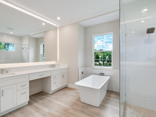 bathroom featuring plus walk in shower, tile walls, and vanity