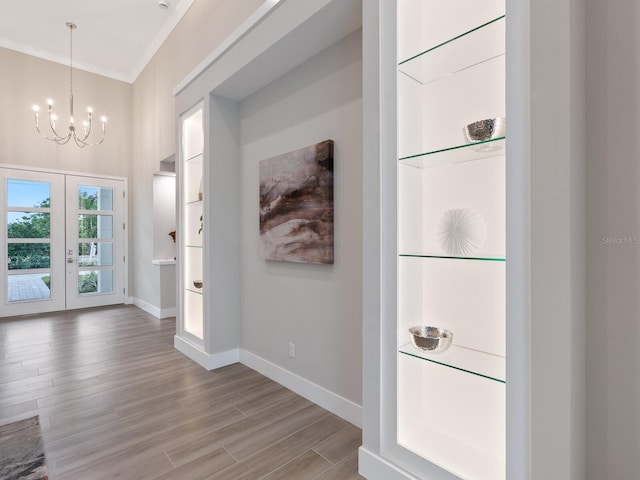 interior space featuring french doors, light hardwood / wood-style flooring, ornamental molding, and a notable chandelier