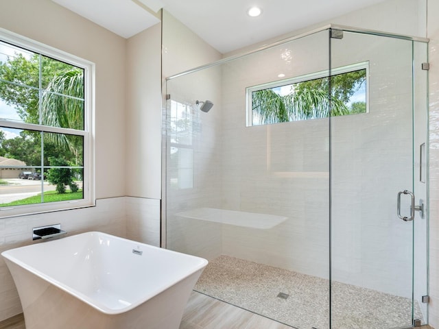 bathroom featuring tile walls, hardwood / wood-style floors, and plus walk in shower