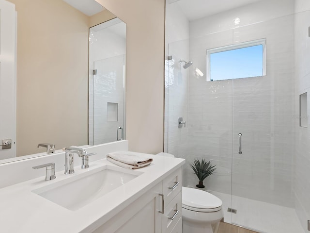 bathroom with toilet, vanity, and a shower with shower door