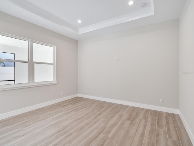 empty room with light hardwood / wood-style flooring and a raised ceiling