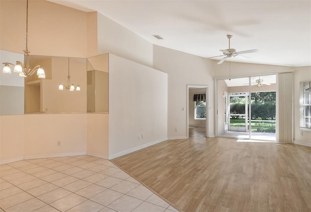 spare room with ceiling fan with notable chandelier, visible vents, baseboards, vaulted ceiling, and light wood-style floors