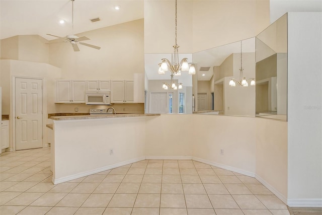 kitchen with light tile patterned floors, visible vents, white microwave, light countertops, and pendant lighting