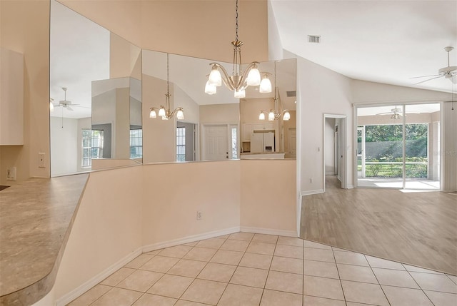 kitchen featuring light tile patterned floors, white refrigerator with ice dispenser, open floor plan, hanging light fixtures, and a healthy amount of sunlight